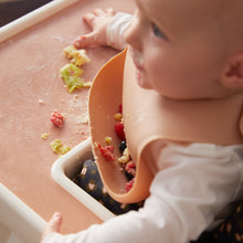 Ladda upp bild till gallerivisning, Ett litet barn som sitter i en barnstol, och som har smulor kvar i sin haklapp