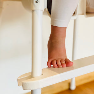 Barns fötter vilande på vitt fotstöd för Ikea Antilop barnstol